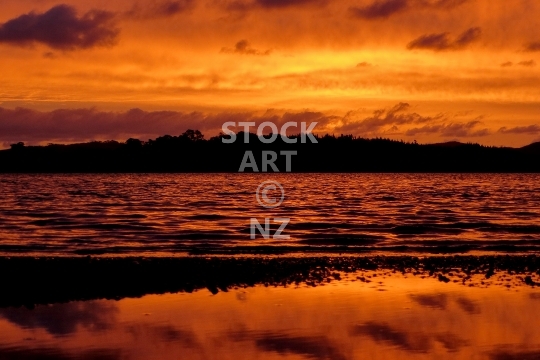 Amazing red Kaipara Harbour sunset  - Beautiful colours and red reflections over the water, reflected over the Tasman Sea and Kaipara Harbour - lower resolution stock photo, ideal for web use