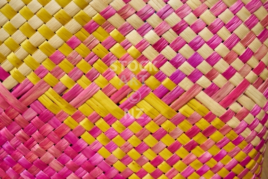 Closeup detail of raranga - kete with pink, magenta, yellow and purple colours