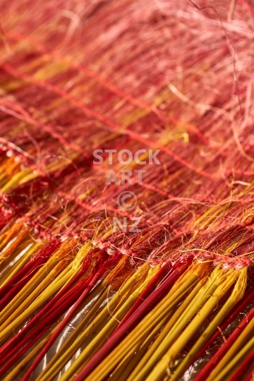 Closeup of a kahu cloak with pokinikini  - New Zealand flax weaving with yellow, red and orange fibres 