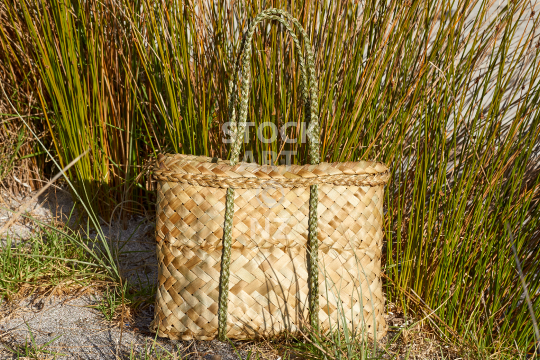 Natural kete on the beach - New Zealand flax weaving bag in nature