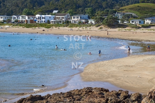 Whangaumu Bay with people swimming 